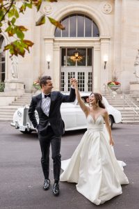 Bride and groom happy in front of a white vintage car at Liberty Grand.