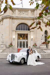 Bride and groom pose with Rolls Royce at Liberty Grand.