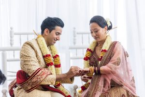 Groom placing the ring on the bride’s finger during Hindu wedding ceremony at New Fort Hall in Hotel X Toronto.