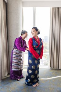Bride sharing a joyful moment with her mother while getting dressed in traditional Tibetan attire at Hotel X Toronto