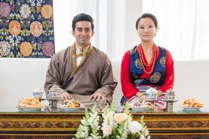 Bride and groom seated during Tibetan wedding ceremony with traditional food and attire at New Fort Hall.