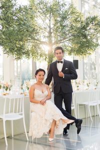 Bride in white dress and groom in tuxedo posing during golden hour at their Hotel X wedding reception.