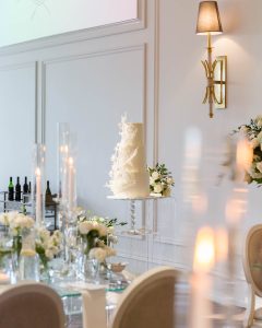 Close-up of white wedding cake with gold accents and floral detailing by Guerdoo Cakes