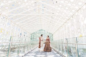 Bride and groom walking hand in hand beneath the geometric white canopy at Hotel X Toronto before their New Fort Hall wedding ceremony.